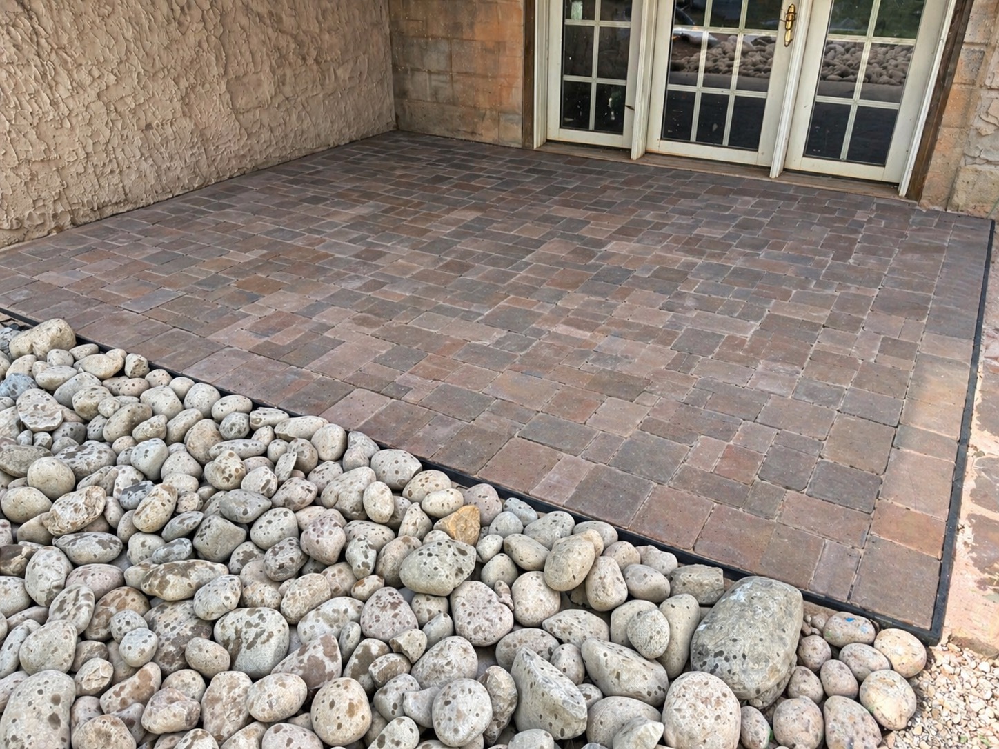 Paver patio with white river-rock decorative stone border — Garrison Landscaping