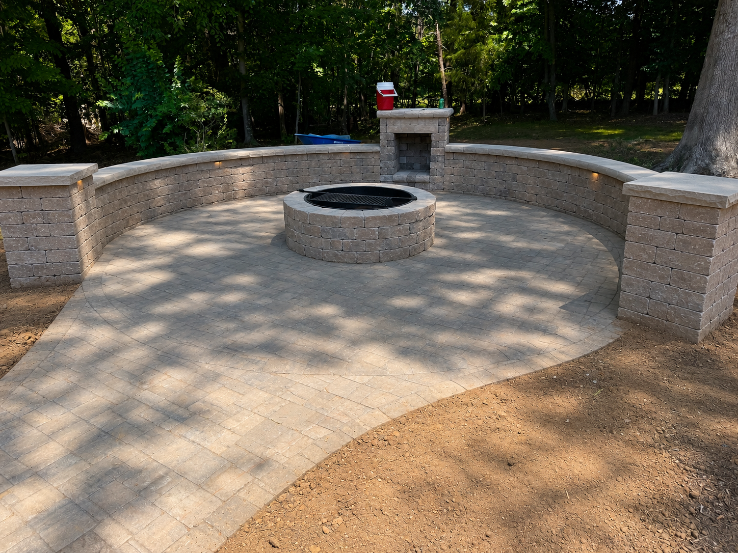Circular paver patio with round fire pit and curved seating wall — Garrison Landscaping