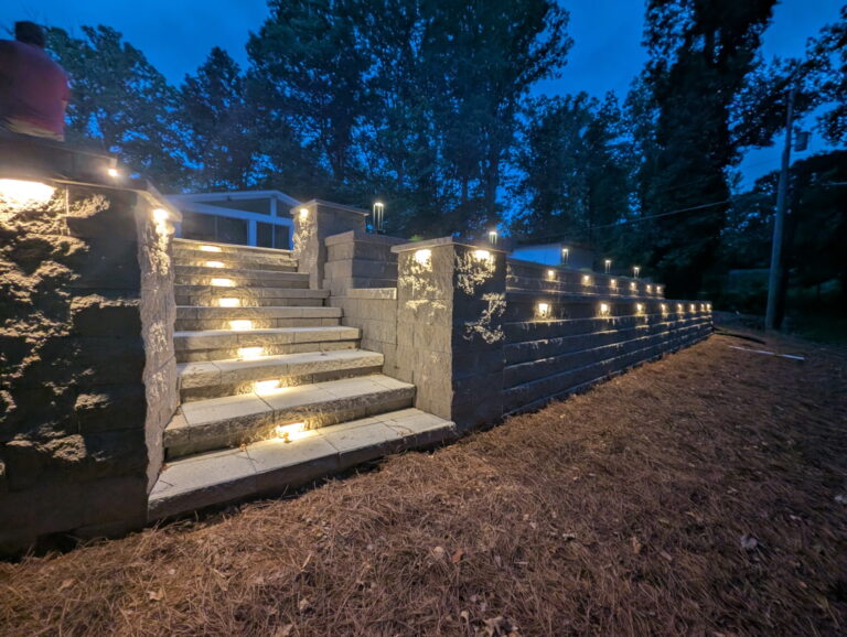 Low-voltage landscape lighting illuminating a stacked stone retaining wall staircase in a North Carolina backyard