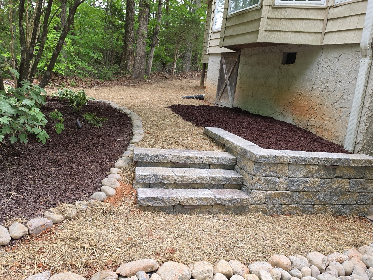 Stacked stone outdoor steps with fresh dark mulch beds — Garrison Landscaping