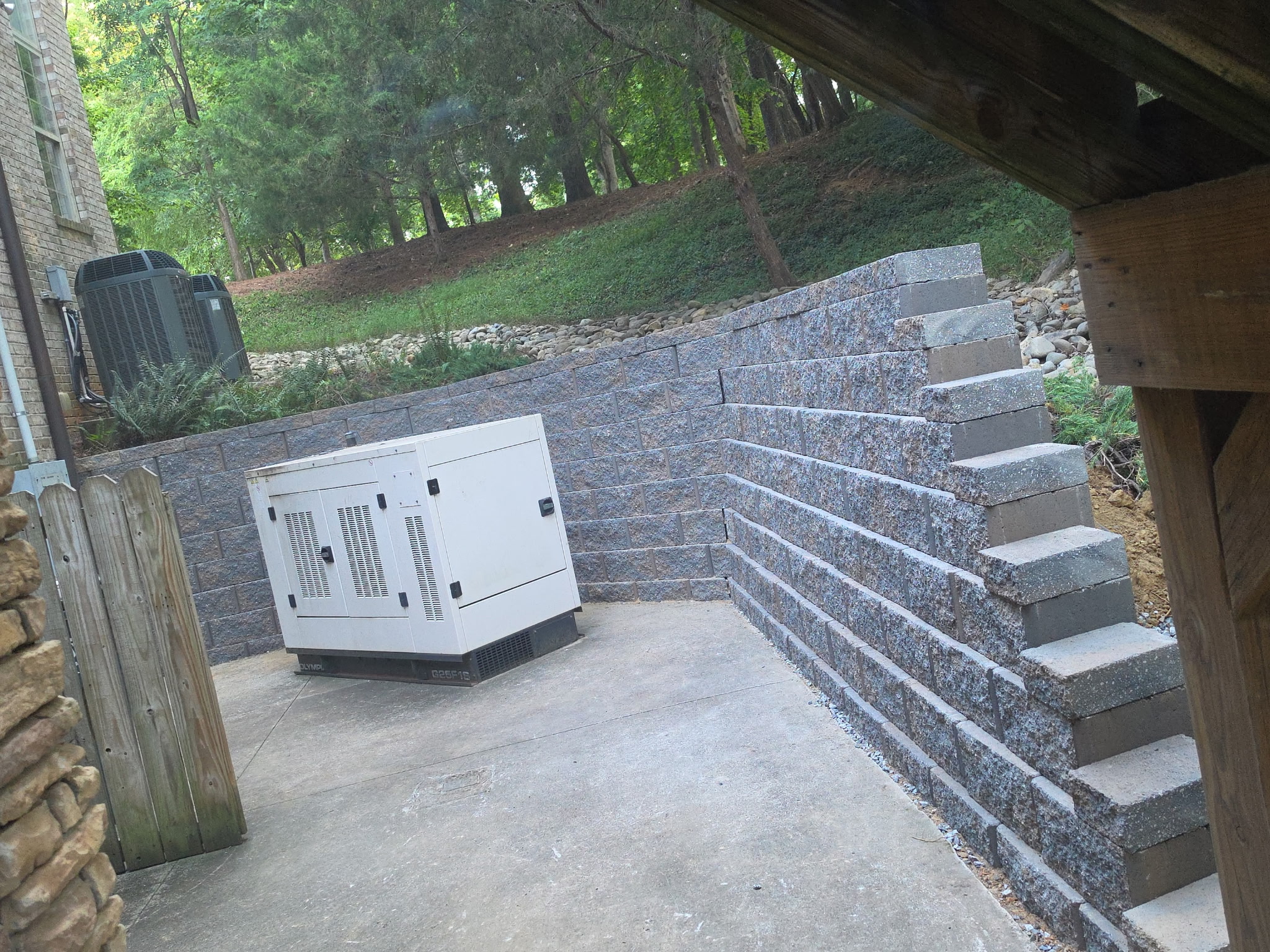 Structural block retaining wall with stepped end and concrete pad — Garrison Landscaping