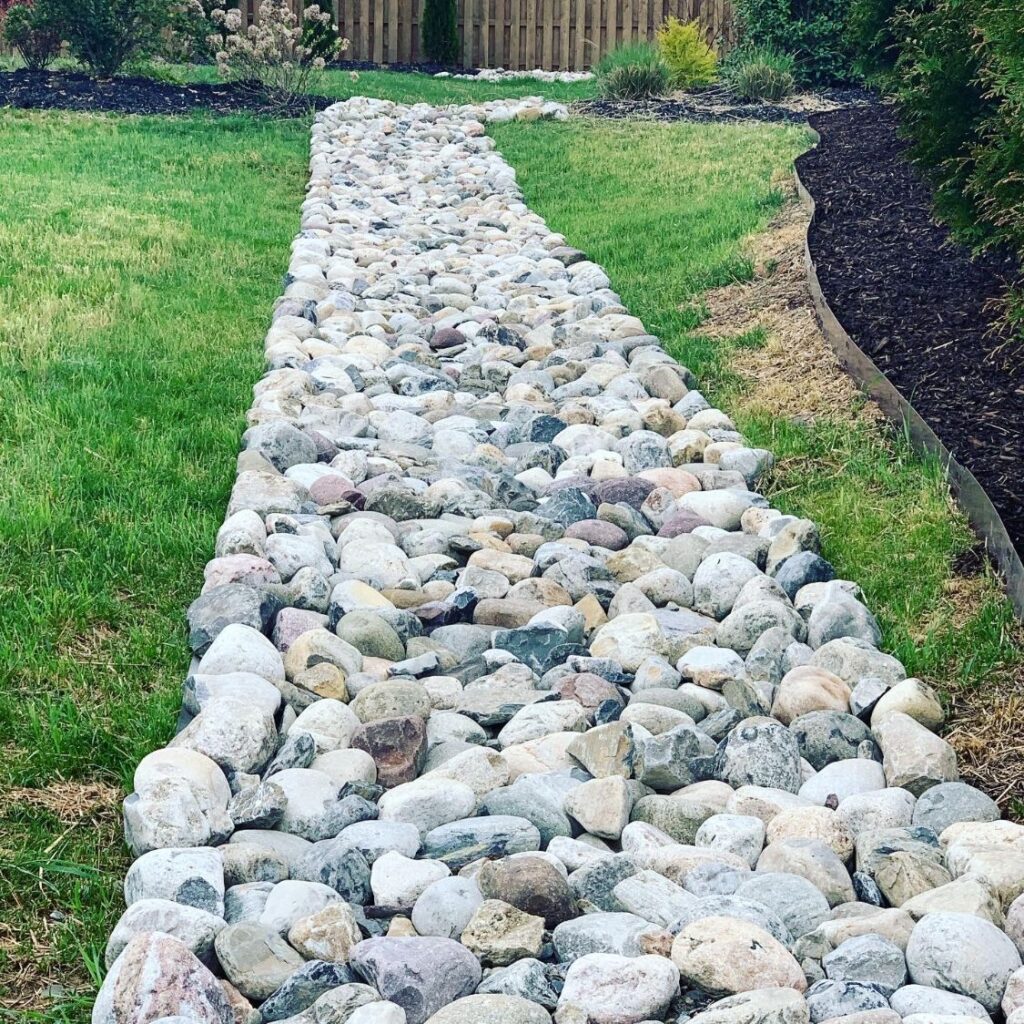 Yard Drainage Solutions Explained: French Drains, Regrading and Downspout Lines 2 Multicolor river rock dry creek bed running through a backyard lawn