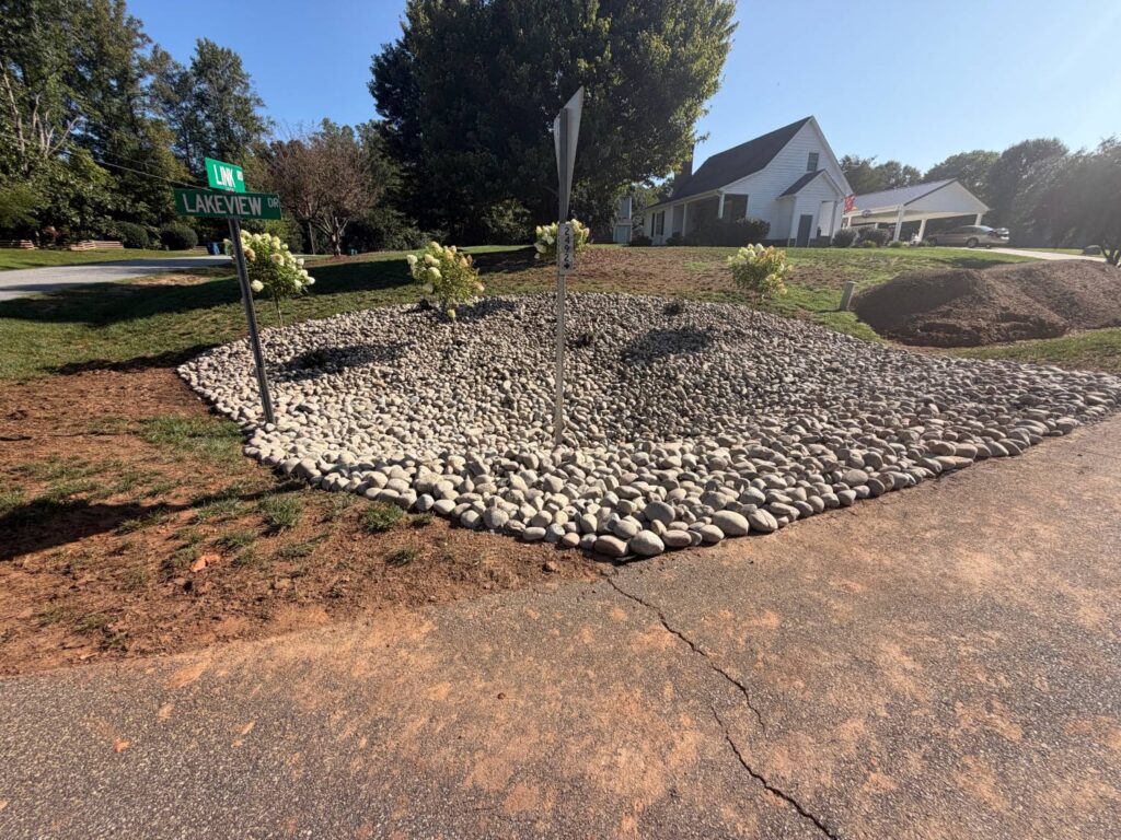 Yard Drainage Solutions Explained: French Drains, Regrading and Downspout Lines 5 River rock bed with hydrangea trees at a street corner, built to control runoff