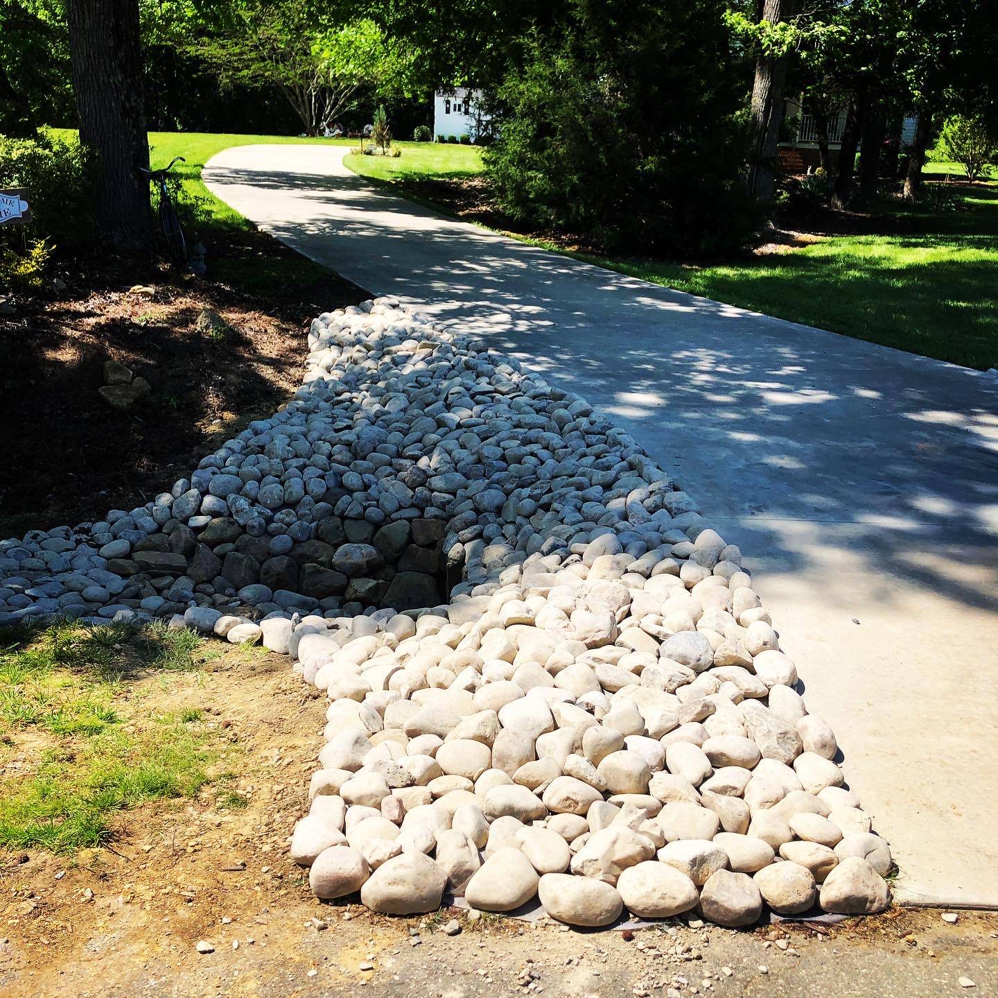 Driveway culvert with a stacked stone headwall and river rock apron