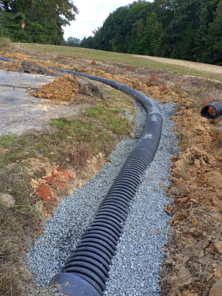Yard Drainage Solutions Explained: French Drains, Regrading and Downspout Lines 3 Large corrugated drain pipe installed on a gravel bed in an open trench