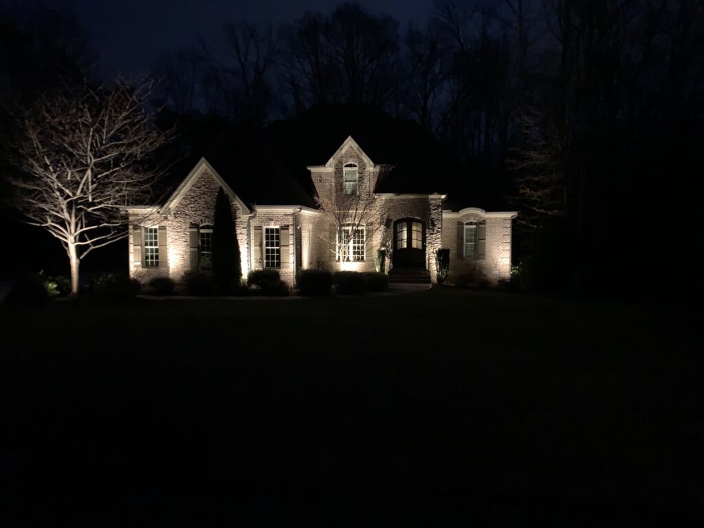 Landscape Lighting Guide: How to Light Your Home and Outdoor Living Spaces 2 Brick home facade with wall washing and uplit ornamental trees at night