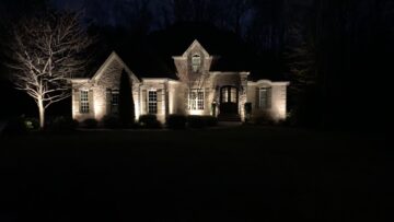 Brick home facade with wall washing and uplit ornamental trees at night