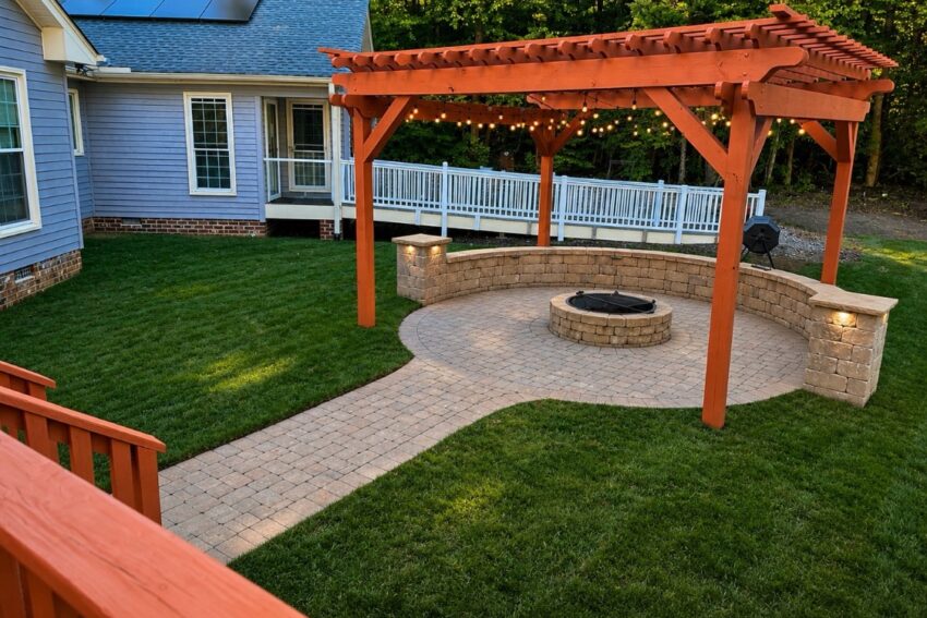 Round paver fire pit patio with a curved stone seating wall, cedar pergola and string lights