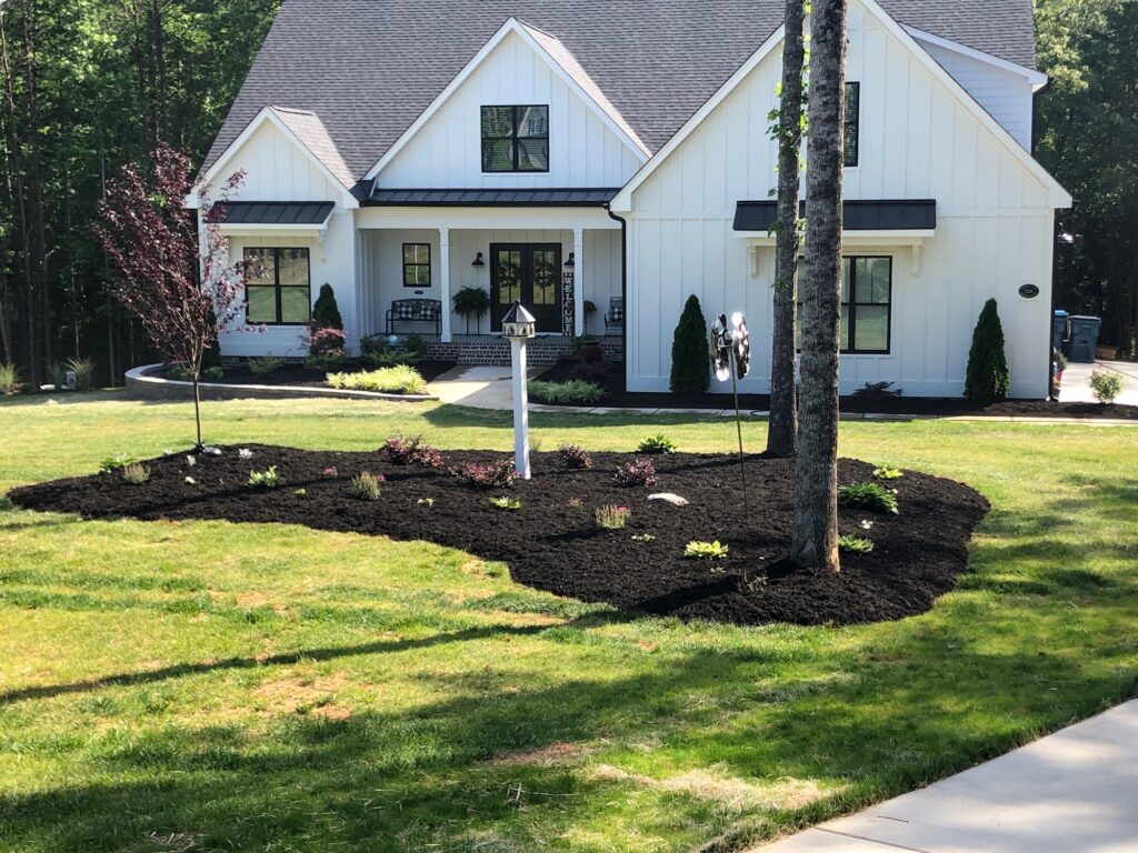 Large mulched landscape beds and plantings in front of a new home