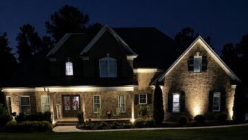 Brick home with warm architectural landscape lighting at night