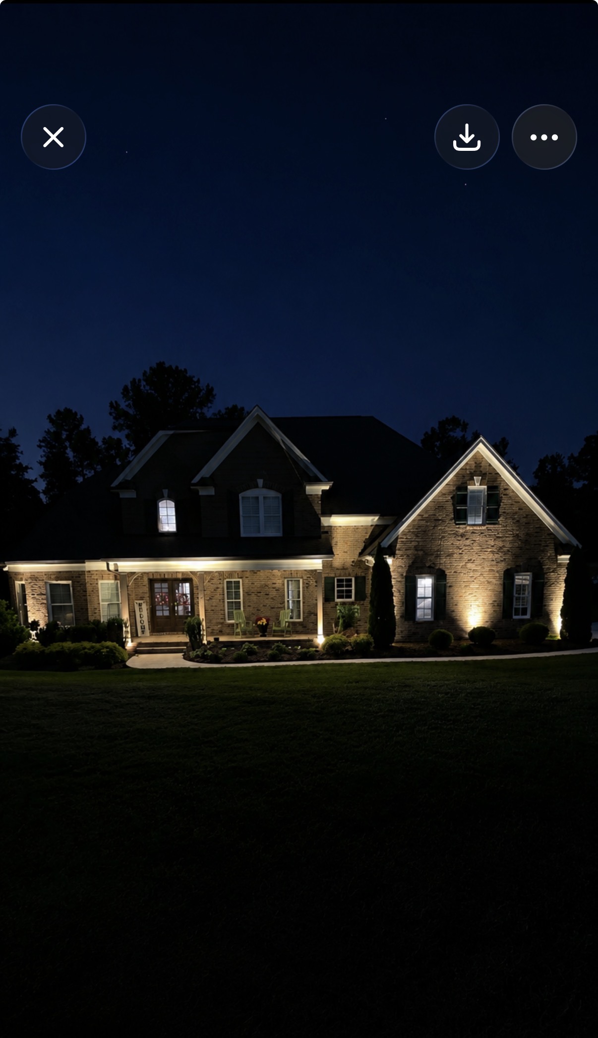 Brick home with warm architectural landscape lighting at night