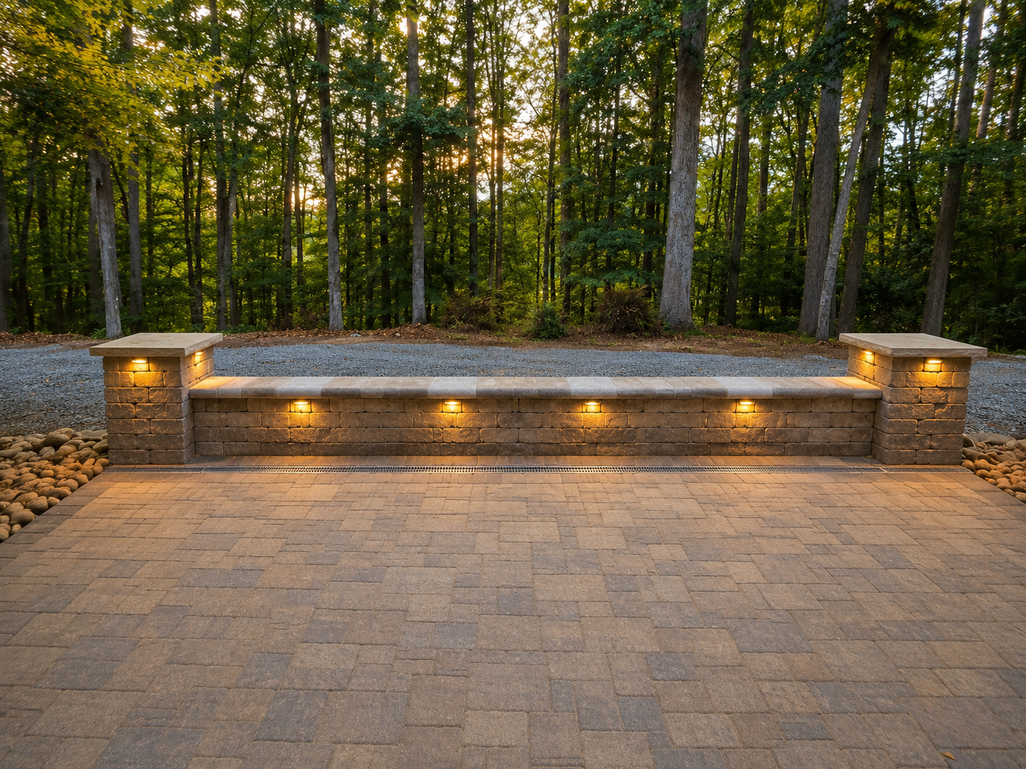 Paver patio with a long seating wall and built-in cap lighting at dusk