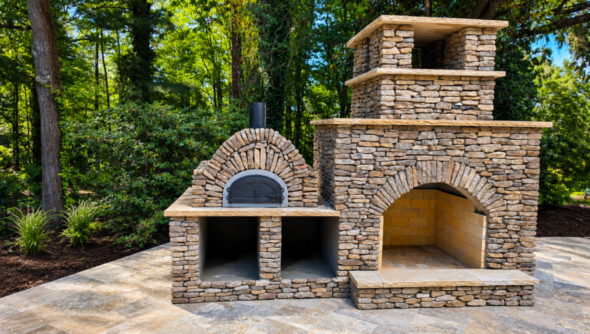 Custom stacked stone outdoor fireplace with built-in pizza oven on a stone patio