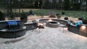 Paver patio with a stone waterfall water feature, seating wall and fire pit