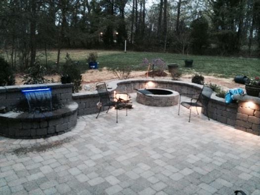 Paver patio with a stone waterfall water feature, seating wall and fire pit