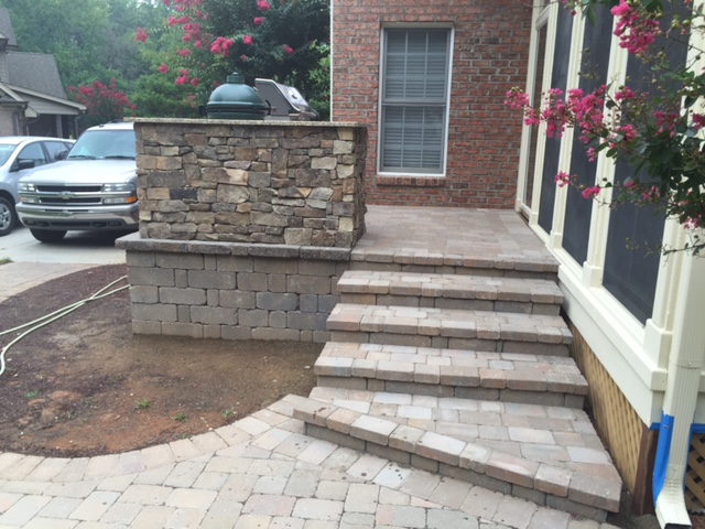 Planning an Outdoor Kitchen in North Carolina: What to Know Before You Build 9 Curved paver steps leading up to a raised patio with a stone-veneer outdoor kitchen and Big Green Egg