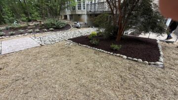 Fresh pine straw ground cover with mulched planting beds and river rock edging