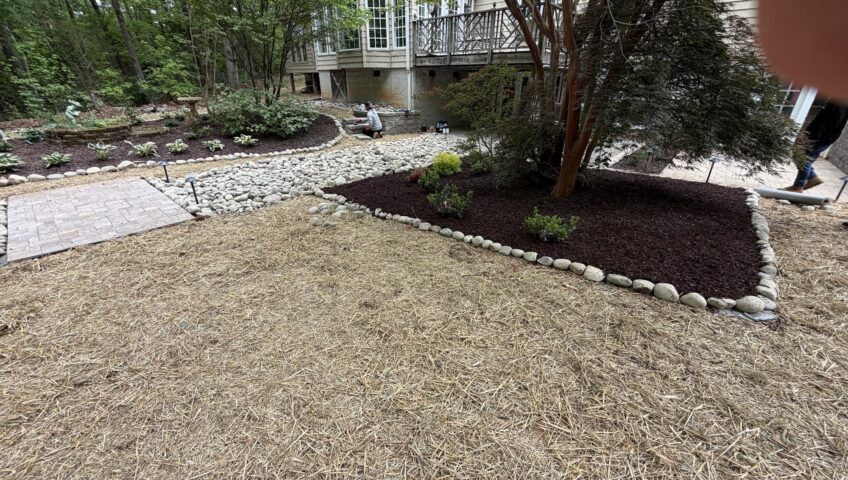 Fresh pine straw ground cover with mulched planting beds and river rock edging