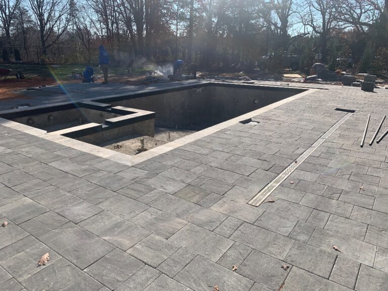 Large-format paver pool deck with coping and trench drain during installation