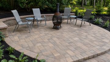 Circular paver patio with a curved block seating wall, chiminea and mulched planting beds