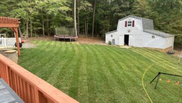 Thick, healthy striped backyard lawn beside a barn