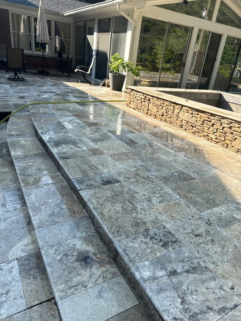 Silver travertine pool patio with curved steps and a stacked-stone raised spa wall
