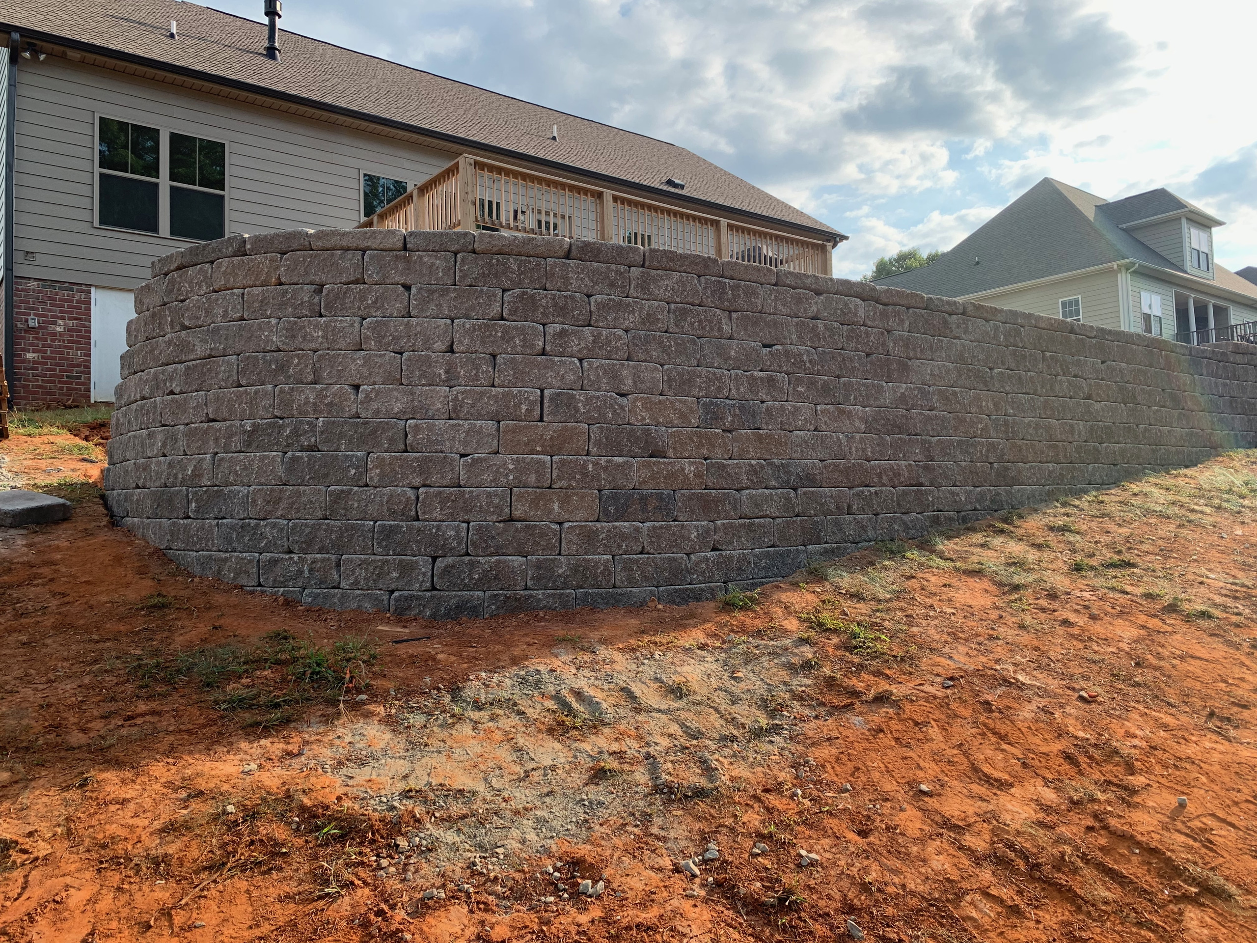 Tall curved segmental block retaining wall supporting a backyard grade in Browns Summit, NC by Garrison's Landscaping