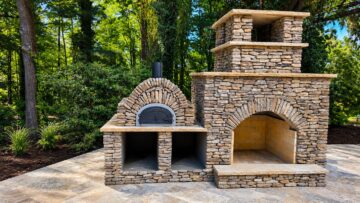 Custom stacked stone outdoor fireplace with built-in pizza oven on a stone patio